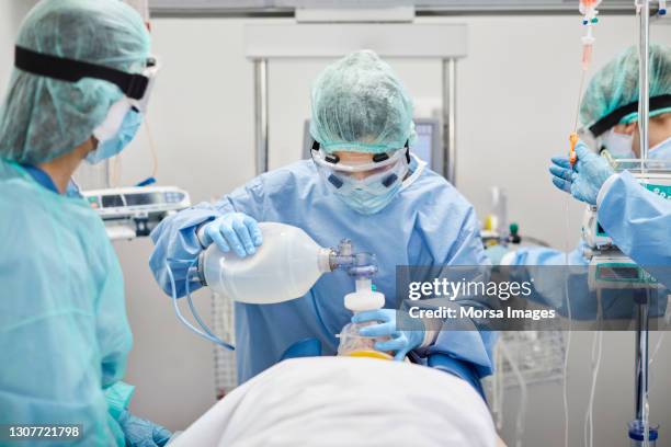 doctors intubating patient in icu during covid-19 - state of emergency stock pictures, royalty-free photos & images