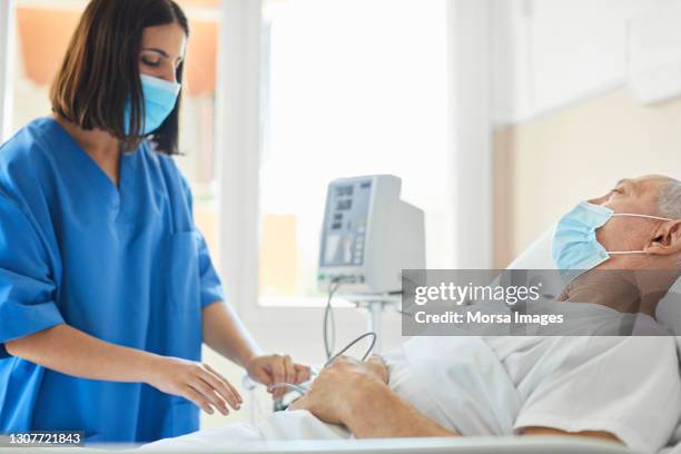 nurse adjusting pulse meter on patient in ward - icu ward stock pictures, royalty-free photos & images