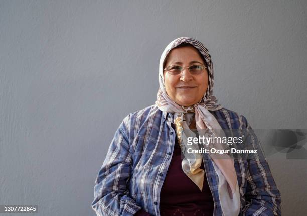 portrait of middle aged muslim woman wearing headscarf, she is sitting in front of a gray wall, mugla, turkey - west asia stock pictures, royalty-free photos & images