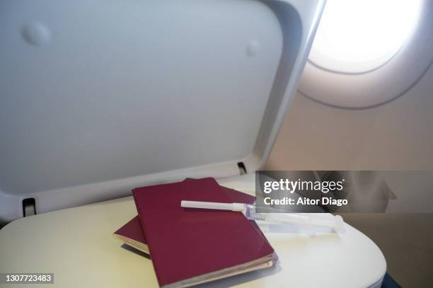 syringe with vaccine and two passports by the side of an airplane window while flying. travel in times of coronavirus with vaccine as passport. - airplane tray table stock pictures, royalty-free photos & images