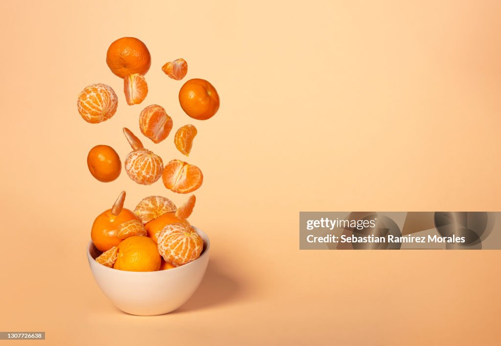 Explosion of tangerines with yellow background, copy space