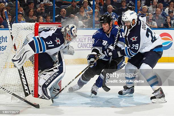Ondrej Pavelec and Johnny Oduya of the Winnipeg Jets defend against a shot by Adam Hall of the Tampa Bay Lightning at the St. Pete Times Forum on...