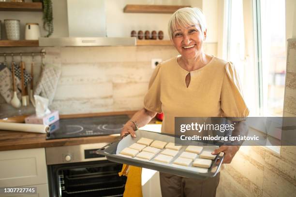 seniorin bereitet sich darauf vor, teig in der küche zu hause zu backen - tablett oder küchenblech stock-fotos und bilder