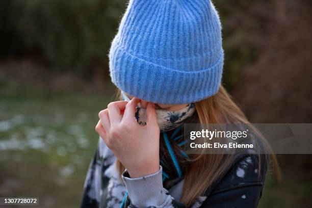 teenage girl wearing protective face mask and rubbing bridge of nose in tension - coronavirus winter bildbanksfoton och bilder