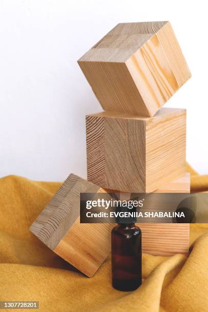 spa cosmetics in brown glass bottles on natural background of wooden cubes and yellow textile. mockup. copy space. - wabi sabi stock pictures, royalty-free photos & images