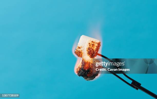 two marshmallows on fire on blue background - marshmallow fotografías e imágenes de stock