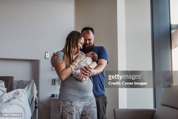 newborn baby boy being cradled by new parents in birthing center - mum dad and baby fotografías e imágenes de stock