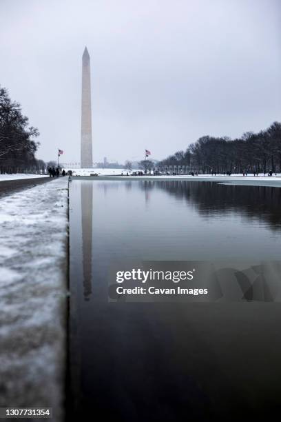 snow blankets the national mall and washington monument in dc. - spiegelteich stock-fotos und bilder