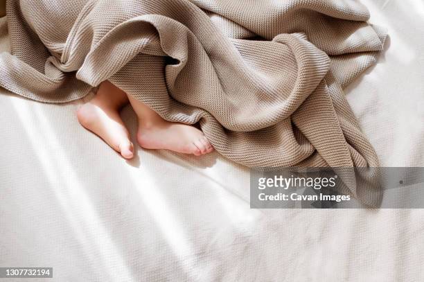 baby little feet covered with lightweight cotton baby knit blanket - baby blankets stockfoto's en -beelden