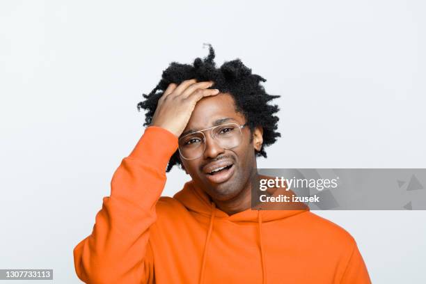 verzweifelter mann in orangefarbenem hoodie - hand in den haaren stock-fotos und bilder
