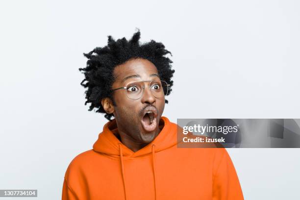 homme étonné dans le sweat à capuche orange - expressions imagées photos et images de collection
