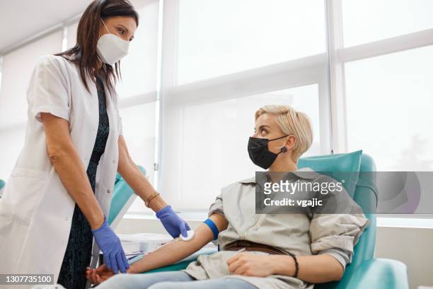 nurse is preparing woman for blood donation - blood bank stock pictures, royalty-free photos & images