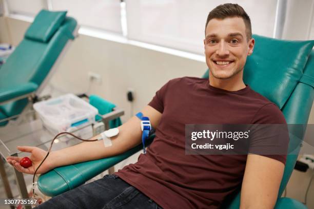 donante masculino joven donando sangre - banco de sangre fotografías e imágenes de stock