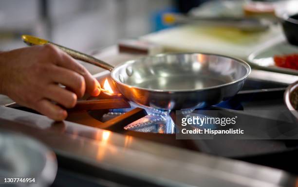 chef zündet einen gasherdbrenner mit einem streichholz an - gas cooking stock-fotos und bilder