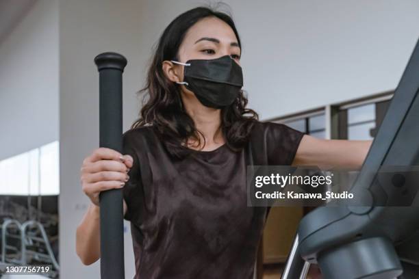 fit asiatische frau übung im fitnessstudio während covid 19 pandemie - face mask with handle stock-fotos und bilder