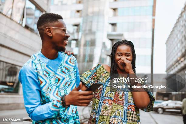 sonriente pareja africana con colorida ropa tradicional pasando tiempo afuera en el centro de la ciudad - tradicional fotografías e imágenes de stock