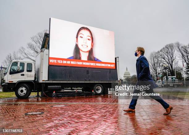 Congressional staff person walks past an installation erected outside of Union Station demanding a Yes vote on the American Dream and Promise Act and...