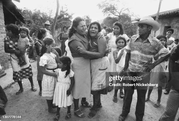 View of people, some embracing and crying, as they await the arrival of a truck carrying the coffins of dead townspeople, Guadalupe, San Vicente...