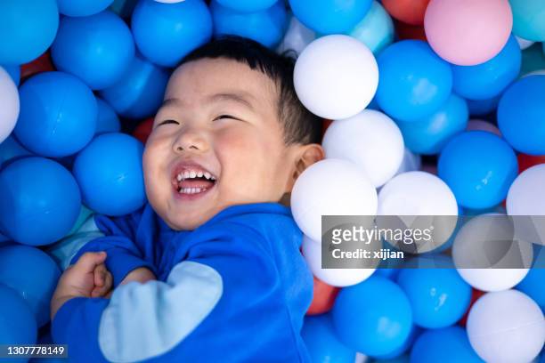 little boy having fun in the ball pool - ball pit stock pictures, royalty-free photos & images