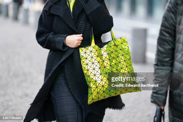 Guest wears a neon yellow pullover, a long oversized black striped rib jacket, a black set stripped pants, a yellow neon Bao Boa Issey Miyake...
