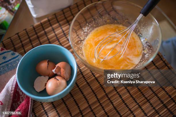 beaten eggs in a glass bowl on the table-stock photo - ballonklopper stockfoto's en -beelden