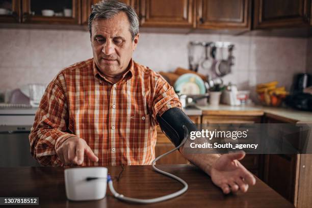 senior man measuring blood pressure - blood pressure gauge stock pictures, royalty-free photos & images