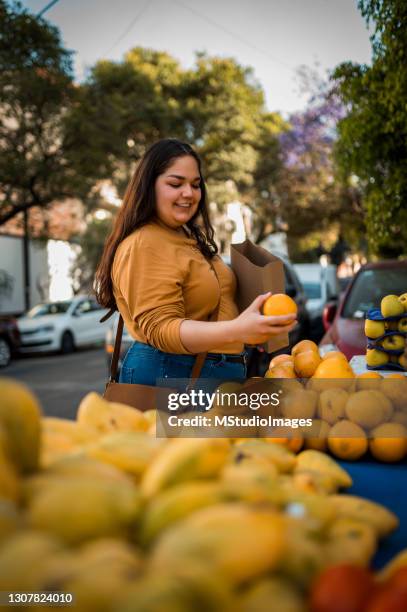 mujer comprando naranja en el mercado local - mercado de productos de granja fotografías e imágenes de stock