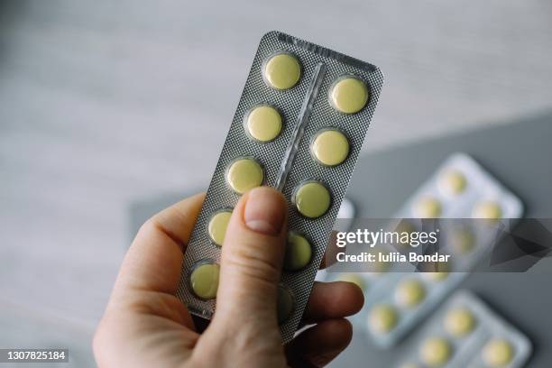 female hand hold pack of yellow tablet blisters. - blister stock pictures, royalty-free photos & images