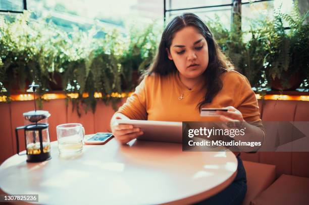 mujer pagando en línea con su tarjeta de crédito - chubby credit fotografías e imágenes de stock