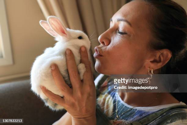 portrait of mid adult woman holding baby rabbit in her hands - pet rabbit stock pictures, royalty-free photos & images