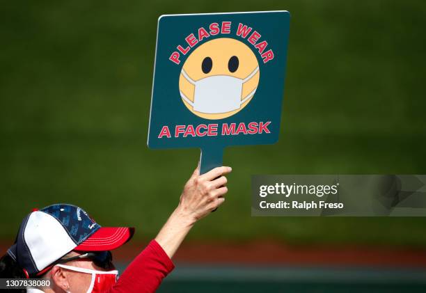 Stadium attendant holds a sign encouraging the use of protective face masks during the MLB spring training baseball game between the Los Angeles...