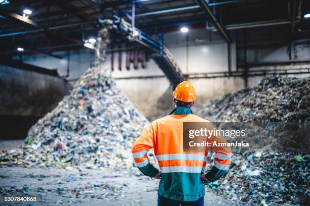 male worker in protective gear at waste processing facility - clothes waste stock pictures, royalty-free photos & images
