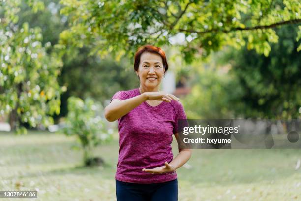 senior asian woman practicing tai chi at public park - woman and tai chi stock pictures, royalty-free photos & images