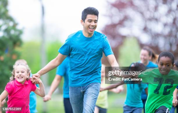 camp counselor läuft mit kindern in einem sommercamp - sommercamp stock-fotos und bilder