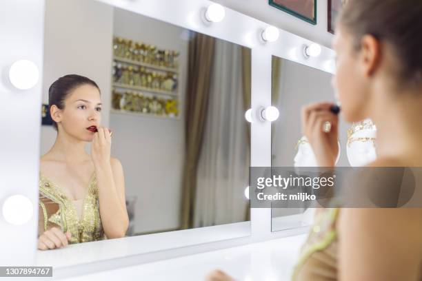 beautiful young ballerina putting lipstick on getting ready to perform - theater backstage stock pictures, royalty-free photos & images