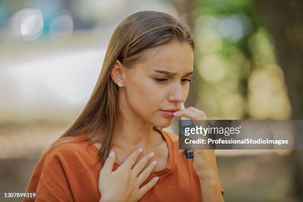 young woman is having sinusitis problems outside in nature. - covering nose stock pictures, royalty-free photos & images