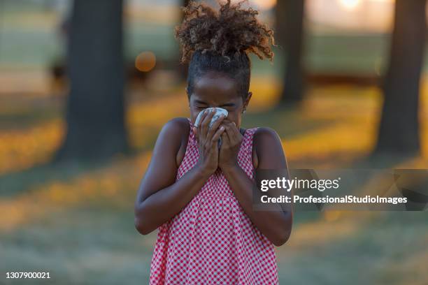 cute little girl with cold or flu is blowing her nose in public park. - sinusitis stock pictures, royalty-free photos & images