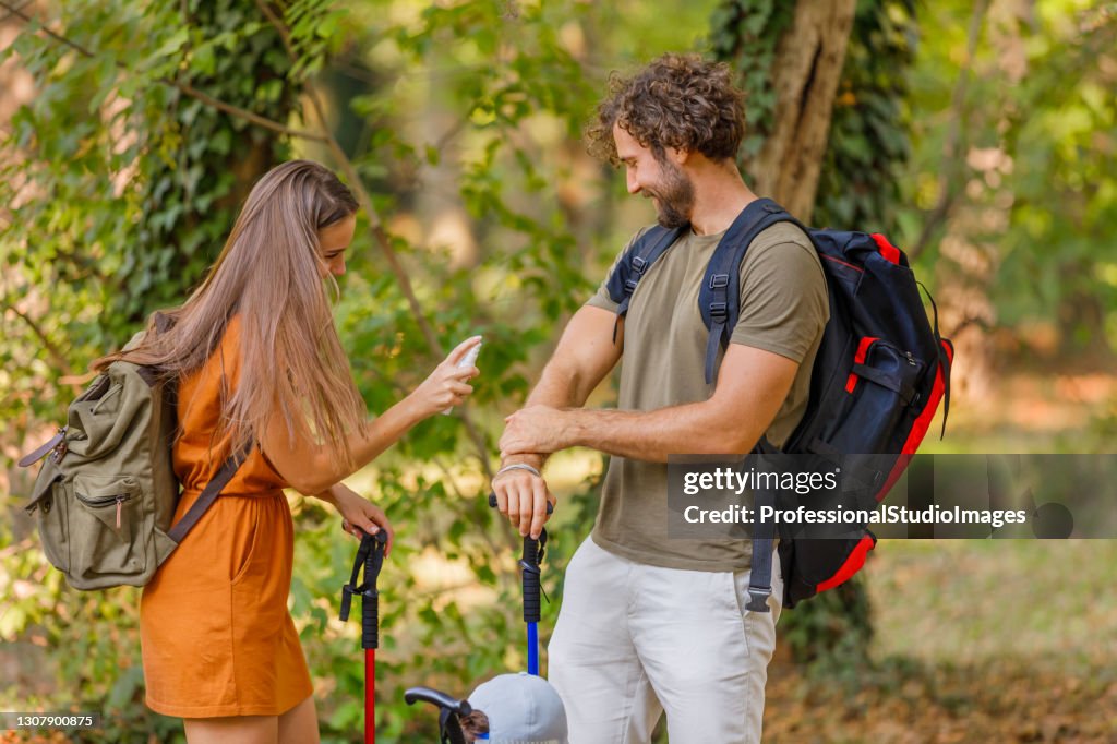 A Young Couple is Traveling with Backpacks and has Problems with Insects in the Forest.
