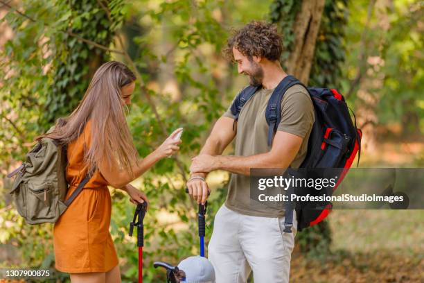 a young couple is traveling with backpacks and has problems with insects in the forest. - mosquito bite stock pictures, royalty-free photos & images