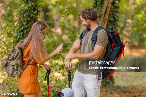 um jovem casal está viajando com mochilas e tem problemas com insetos na floresta. - tick bite - fotografias e filmes do acervo
