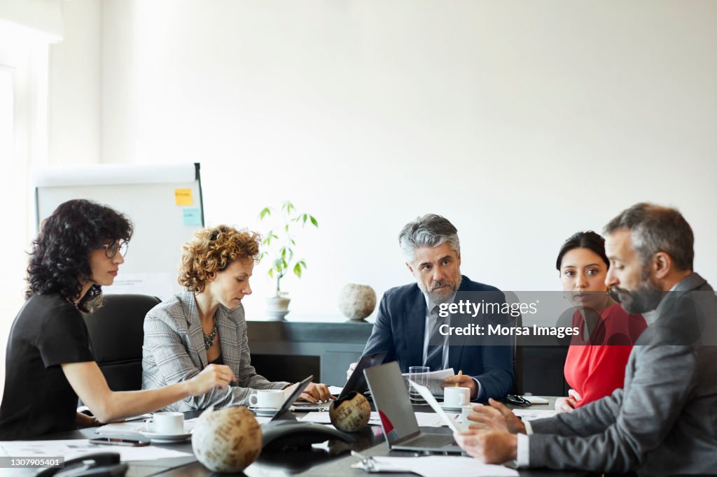 Businessman discussing with coworkers in conference room