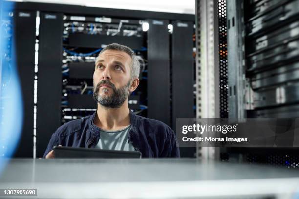 male technician standing in server room - rechenzentrum stock-fotos und bilder