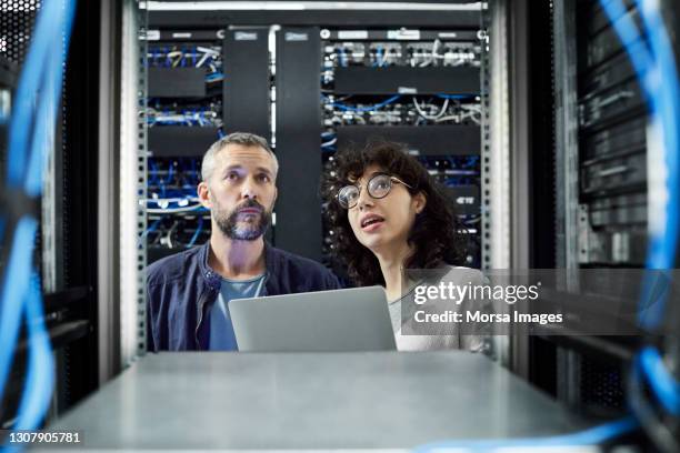 female technician discussing with male coworker in server room - server stock pictures, royalty-free photos & images