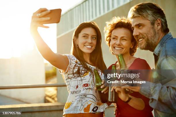 happy male and female friends photographing on rooftop - buenos aires rooftop stock pictures, royalty-free photos & images