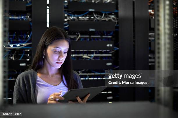 female engineer using digital tablet in server room - server room women foto e immagini stock