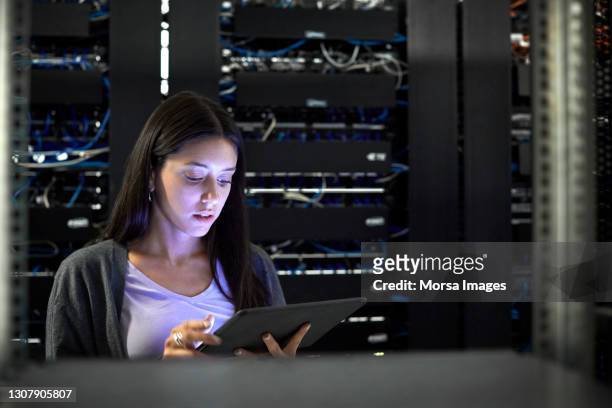 female engineer using digital tablet in server room - telecoms engineer stock pictures, royalty-free photos & images