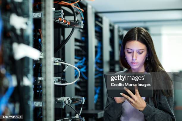 female technician using digital tablet examining in server room - computer cable fotografías e imágenes de stock