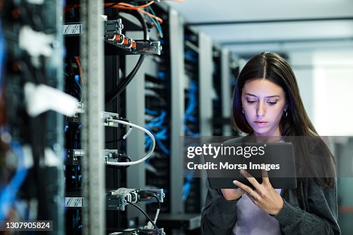 Female technician using digital tablet examining in server room Female technician using digital tablet examining in server room