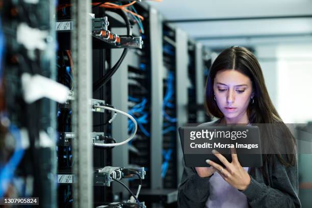 female technician using digital tablet examining in server room - nätserver bildbanksfoton och bilder