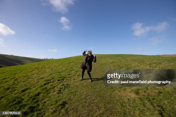 lady with raised fists in field - paul mansfield photography stock-fotos und bilder